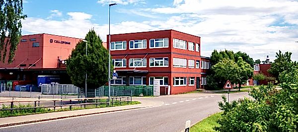 rotes Firmengebäude mit Produktionshalle umgeben von grüner Natur