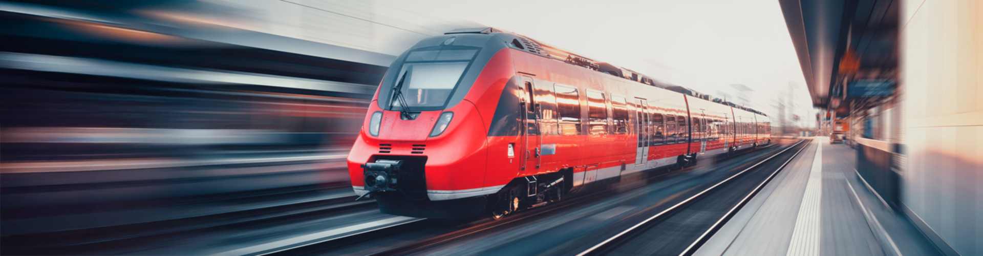 Ein roter Regionalzug fährt durch einen Bahnhof